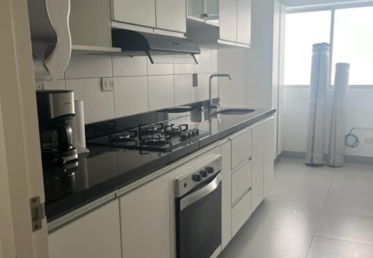 En venta departamento en Miraflores con cocina. Equipada con muebles altos y bajos. Se aprecia el área para una mesita con luz natural desde una ventana grande.